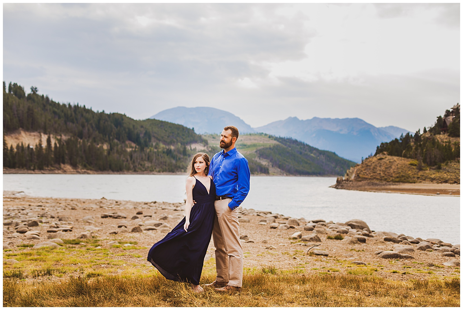 a couple on a lake shore in the mountains