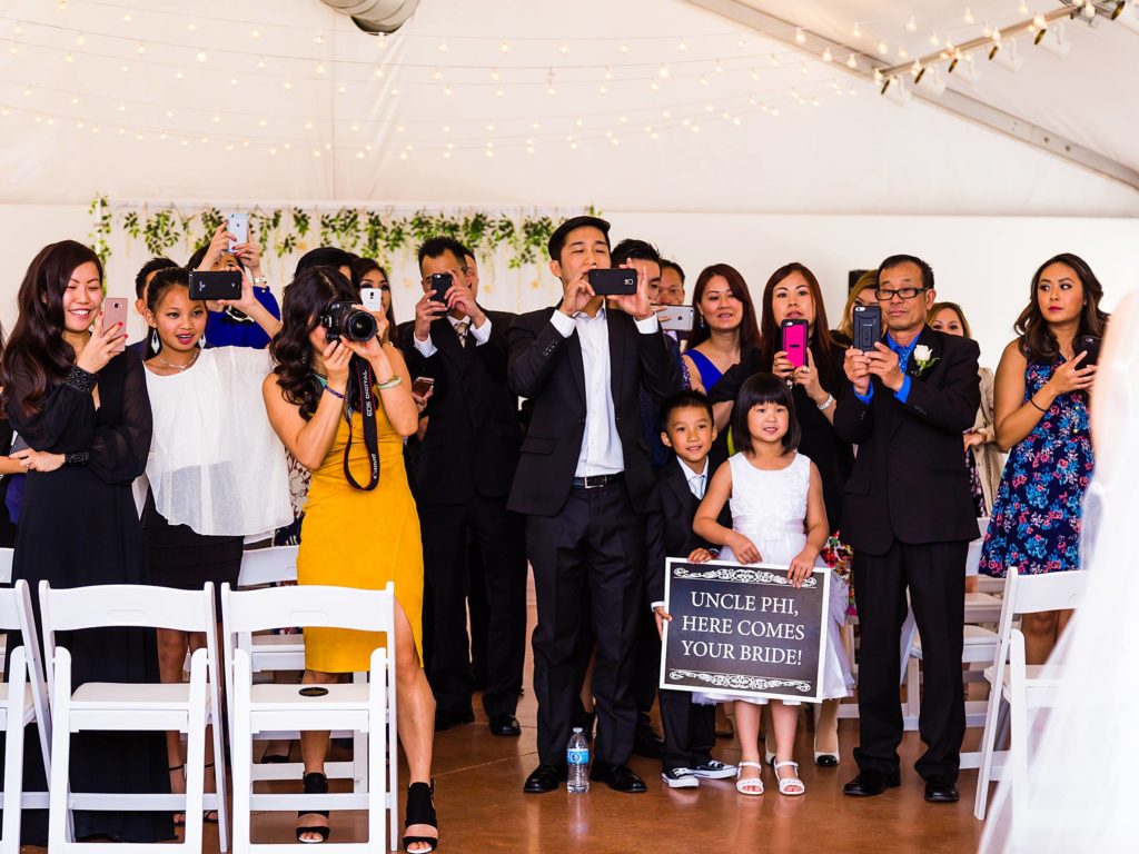 Family taking pictures of wedding couple during ceremony
